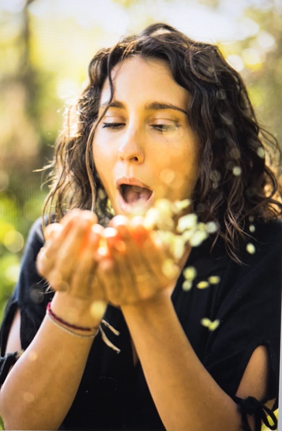 Holly Brinkman blowing a handful of seeds into the sunlight